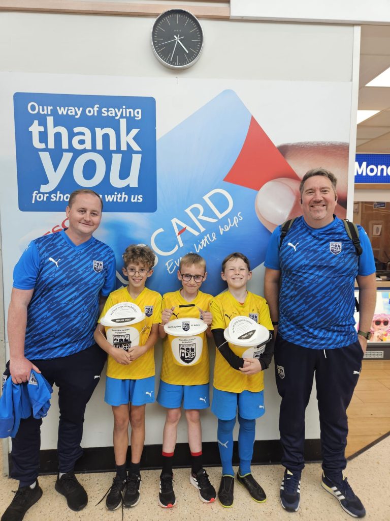 Young footballers and coaches at their local Tesco's with fundraising buckets